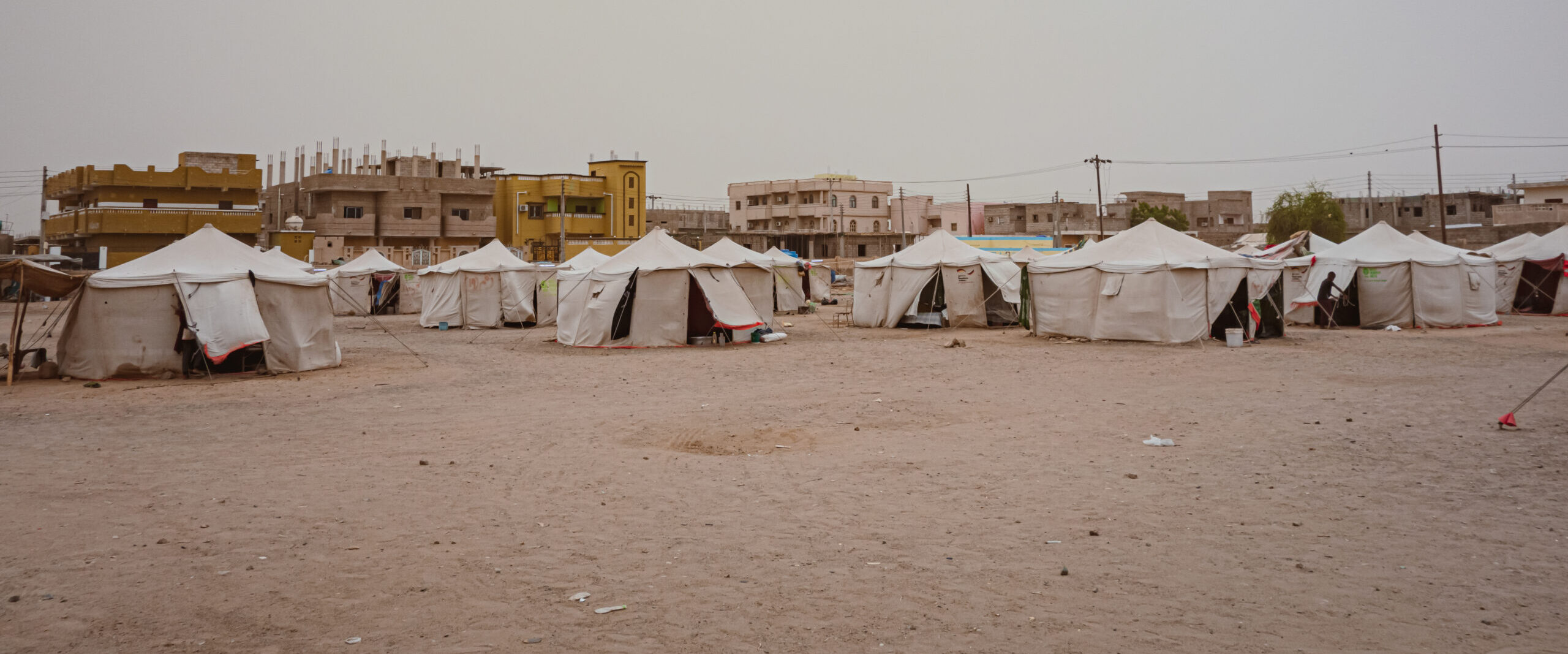 A line of white shelter tends in an area of dry ground
